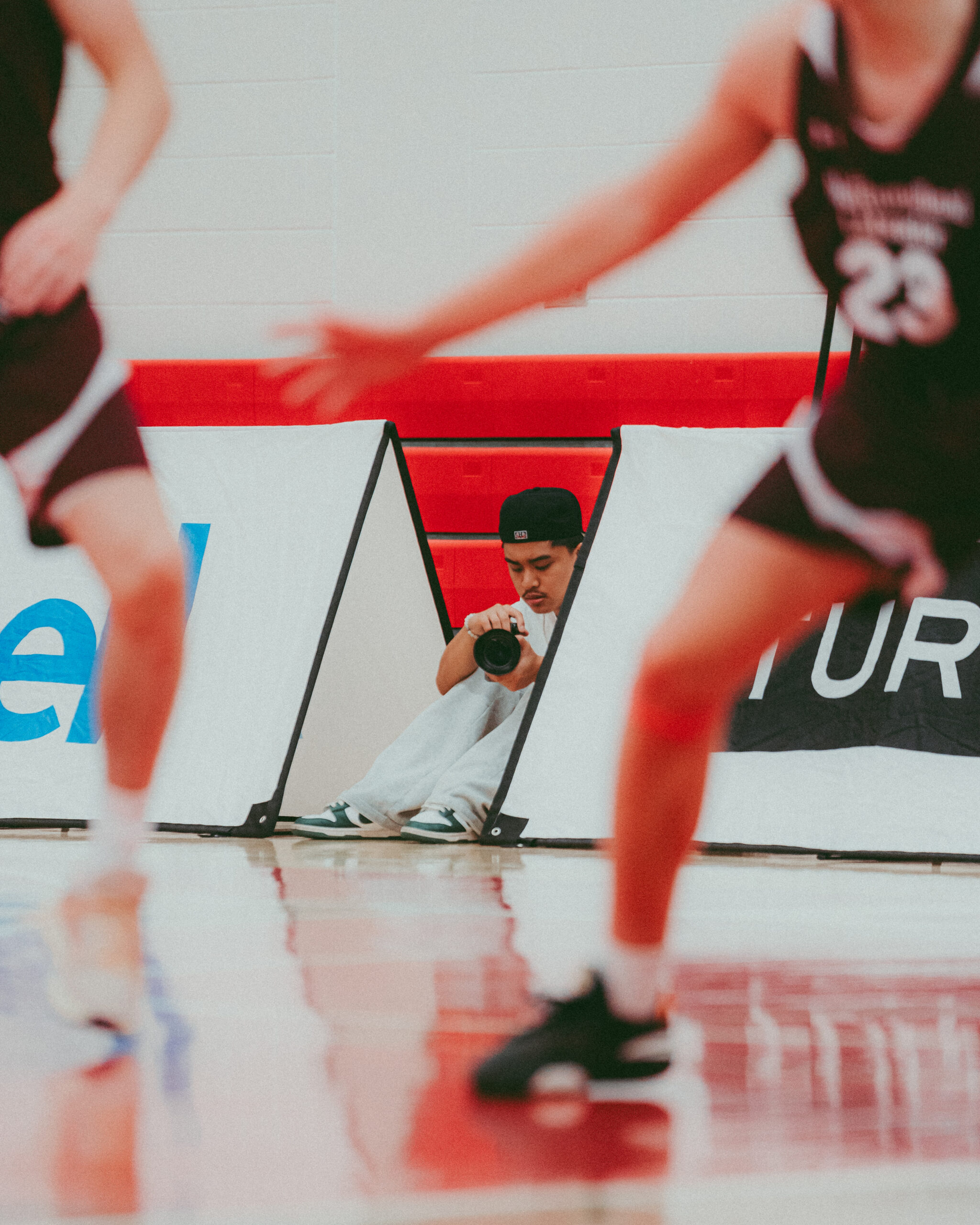 Retrato de um fotógrafo jovem olhando para a câmera com jogadores jovens de basquete em primeiro plano