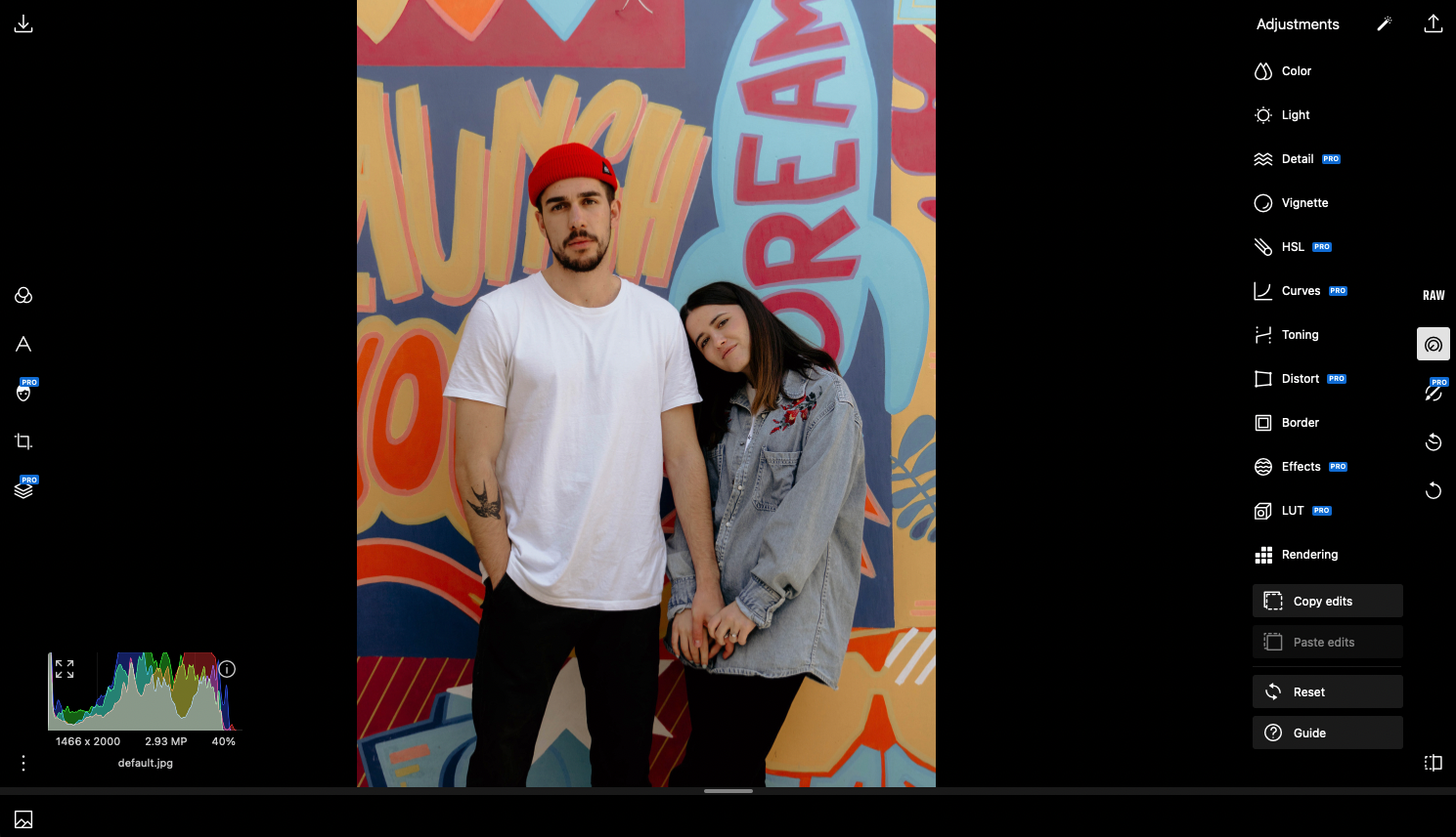 Fotografia de homem e mulher de mãos dadas em frente a um muro grafitado no editor de fotos on-line Polarr.