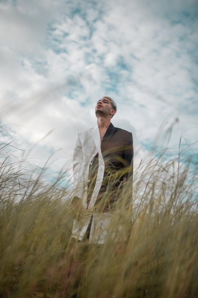 Hombre con traje blanco y negro en un campo cubierto de hierba