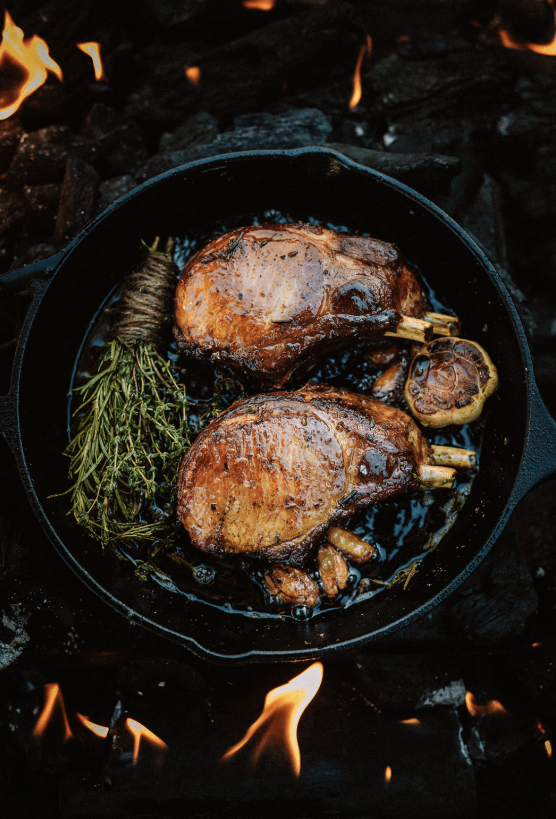 photo of bone in pork chops in a cast iron pan with herbs by John Troxell