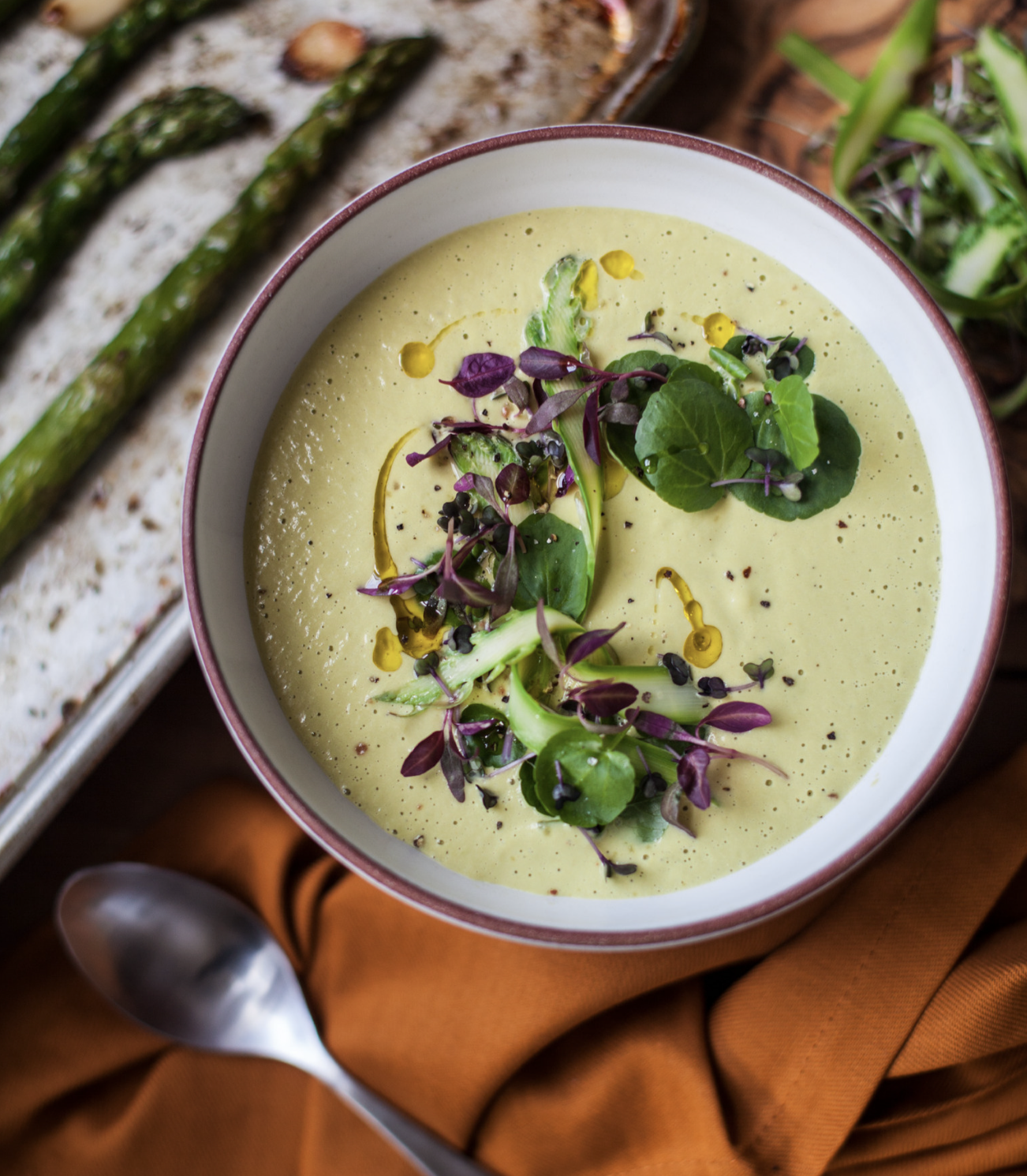 photo of creamy blended soup topped with greens and swirls of oil by yasmin alishav