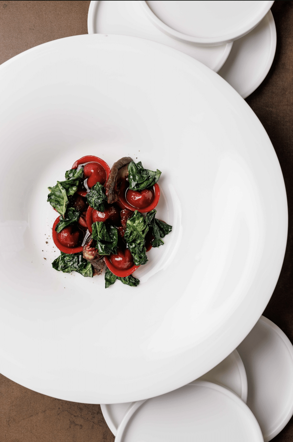 photo of deep red tortelini with greens in a white bowl by AndreaDiLorenzo