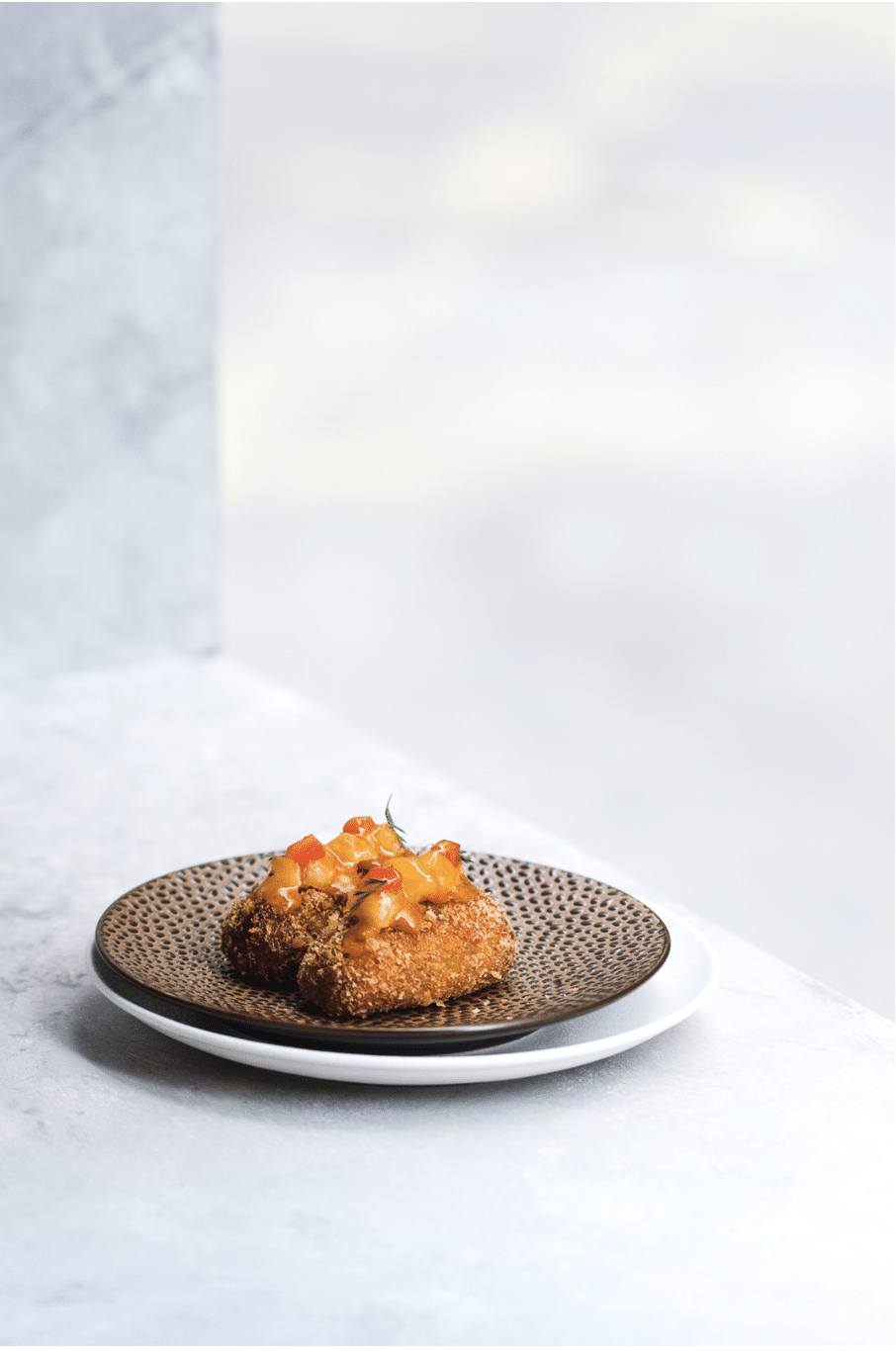 photo of fried food topped with a fruity sauce on a bronze plate by LenkasLens