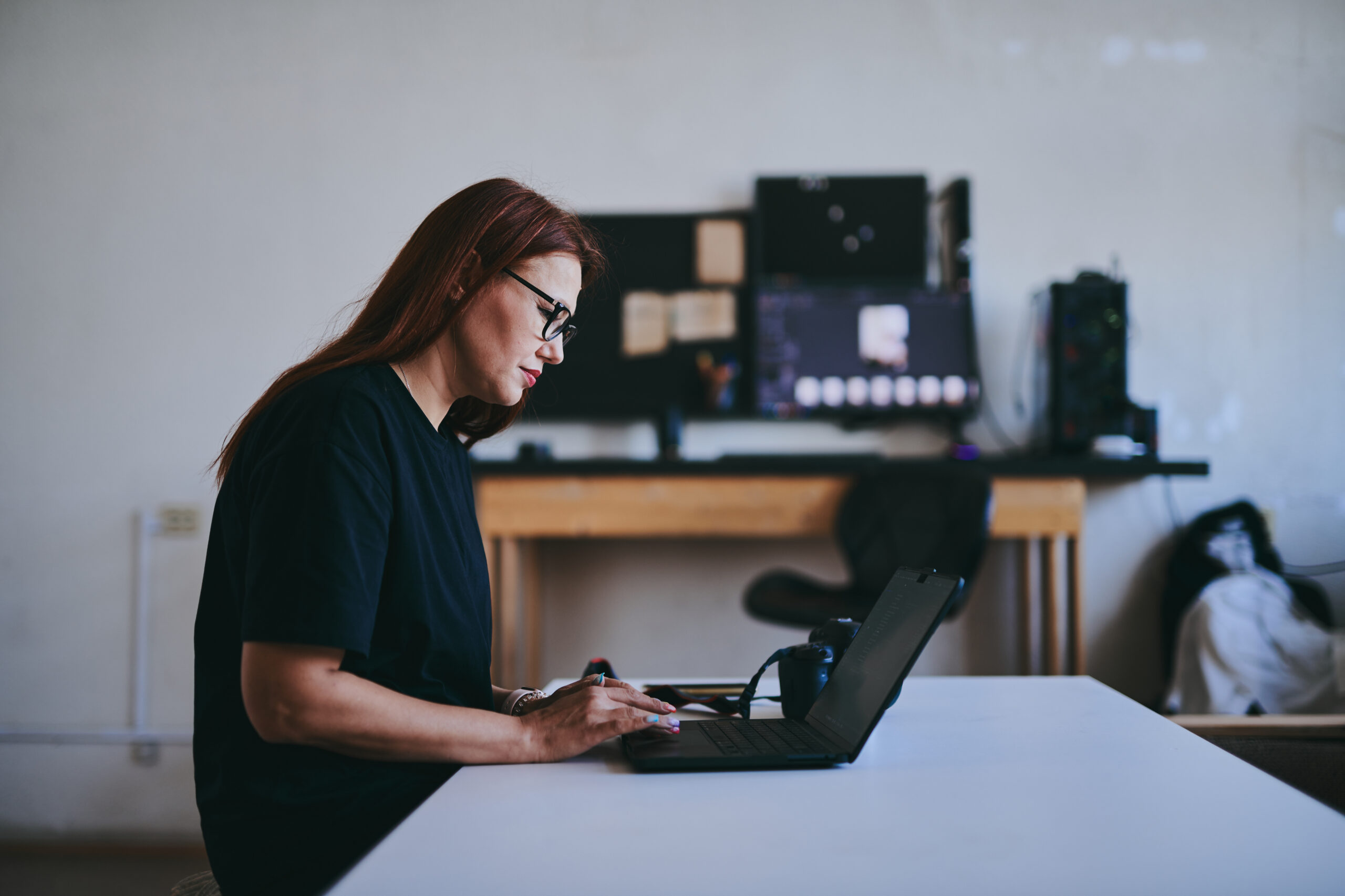 Female photographer with laptop on table processing shots in professional photo studio