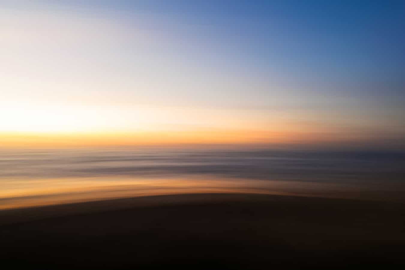 Photo by Anne Healy of a Sunrise at the Beach in Anzac, the soft colors distorted with camera blur