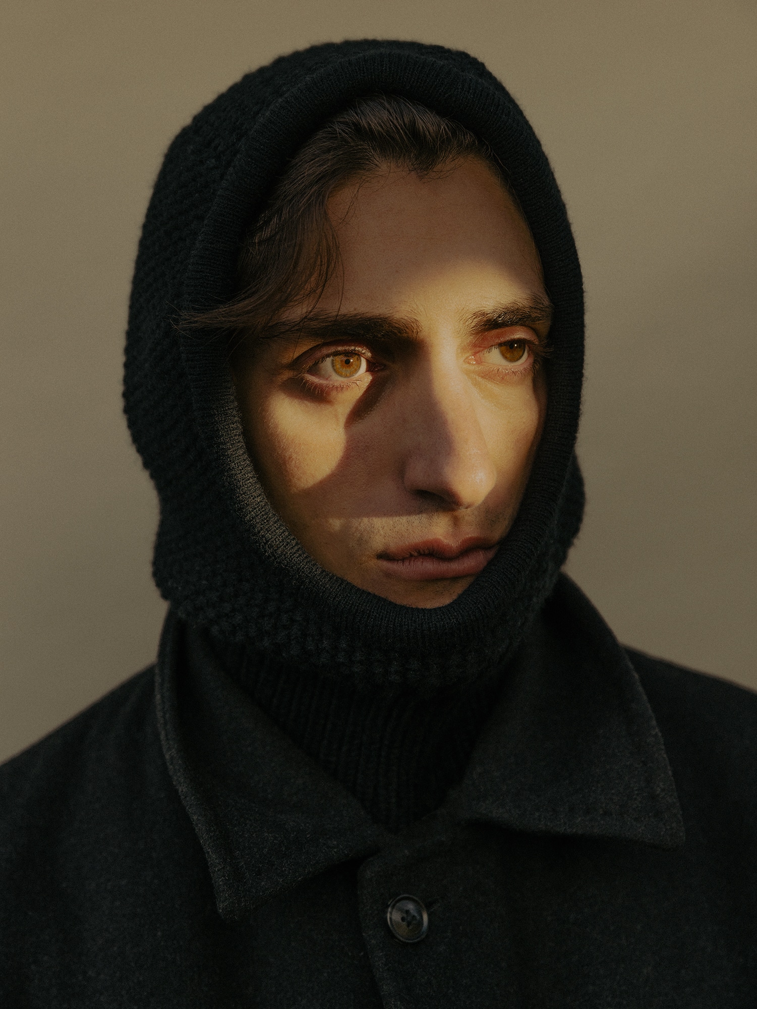 Portrait of a man with his face in light and shadows, his head and shoulders wrapped black fabric. Photo by Grant Harder 3