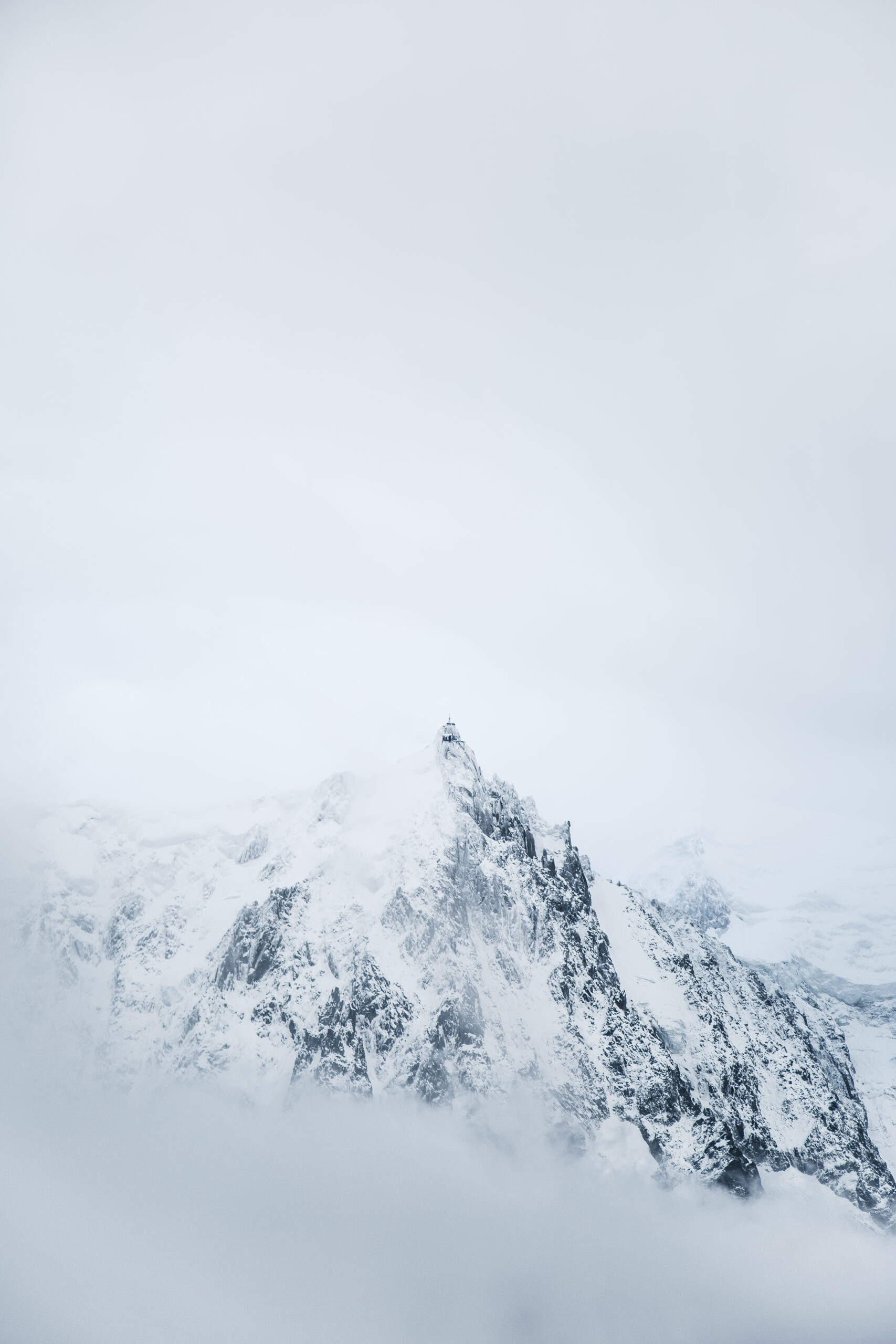 photograph of a craggy and snow-covered mountain surrounded by mists by Mayank Thammalla