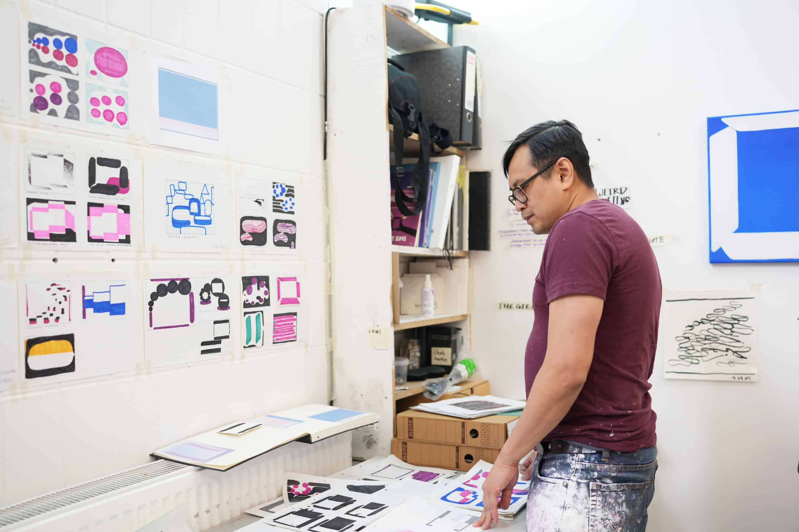 Nam Duc Nguyen mirando bocetos junto a una mesa en su estudio de Berlín.