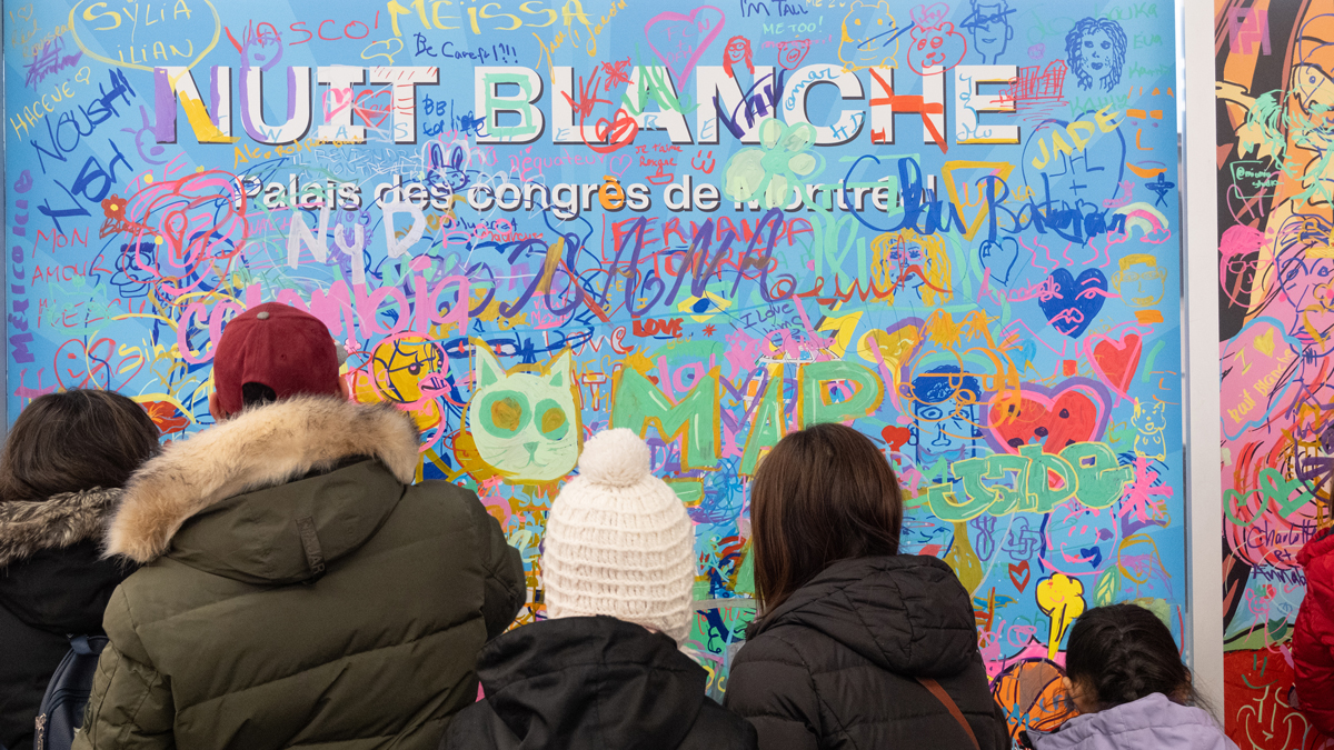 Nuit Blanche sign at palais des congres covered in doodles from festival-goers with paint markers.