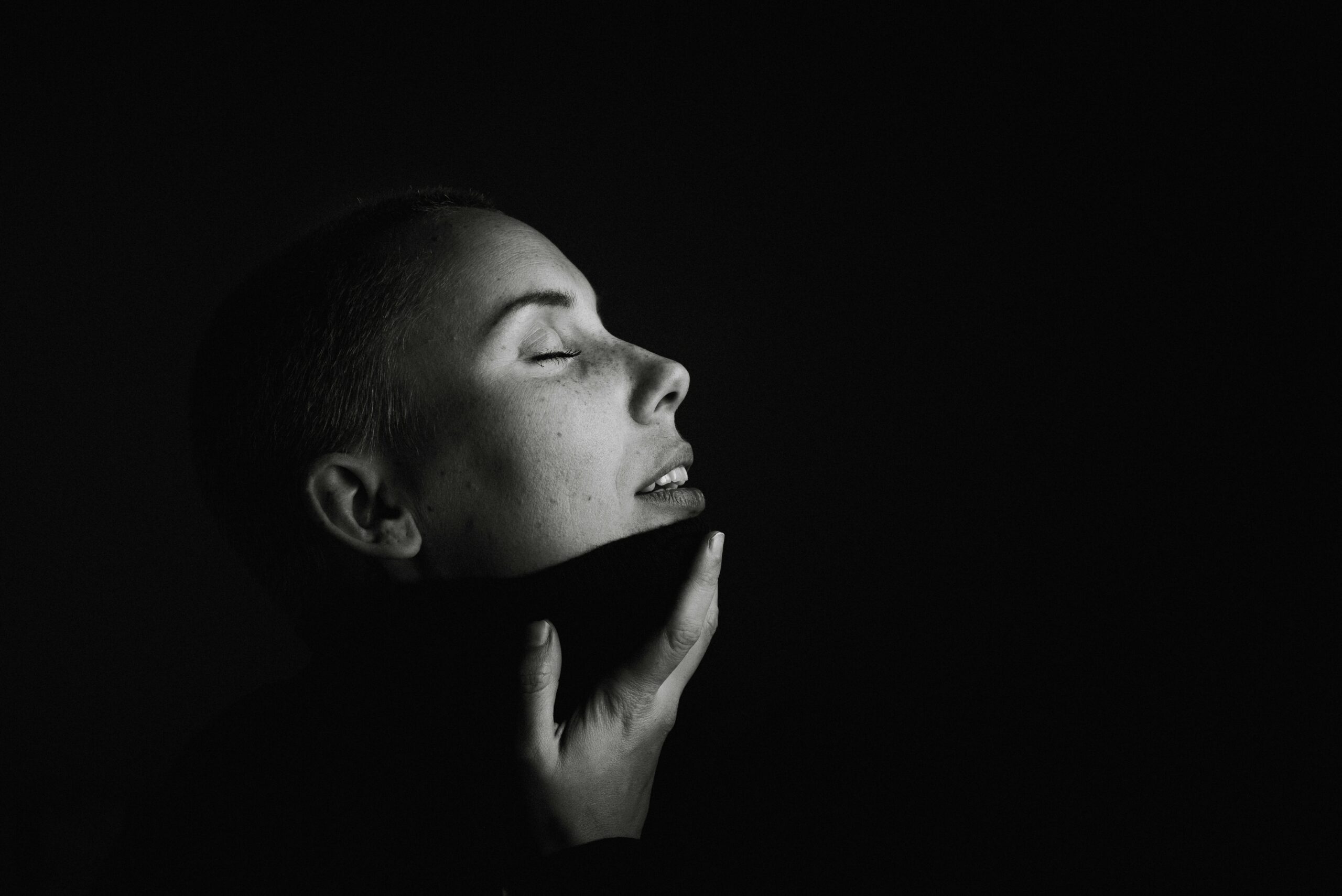 portrait d'une femme en noir et blanc, la main sur le menton, à l'échelle