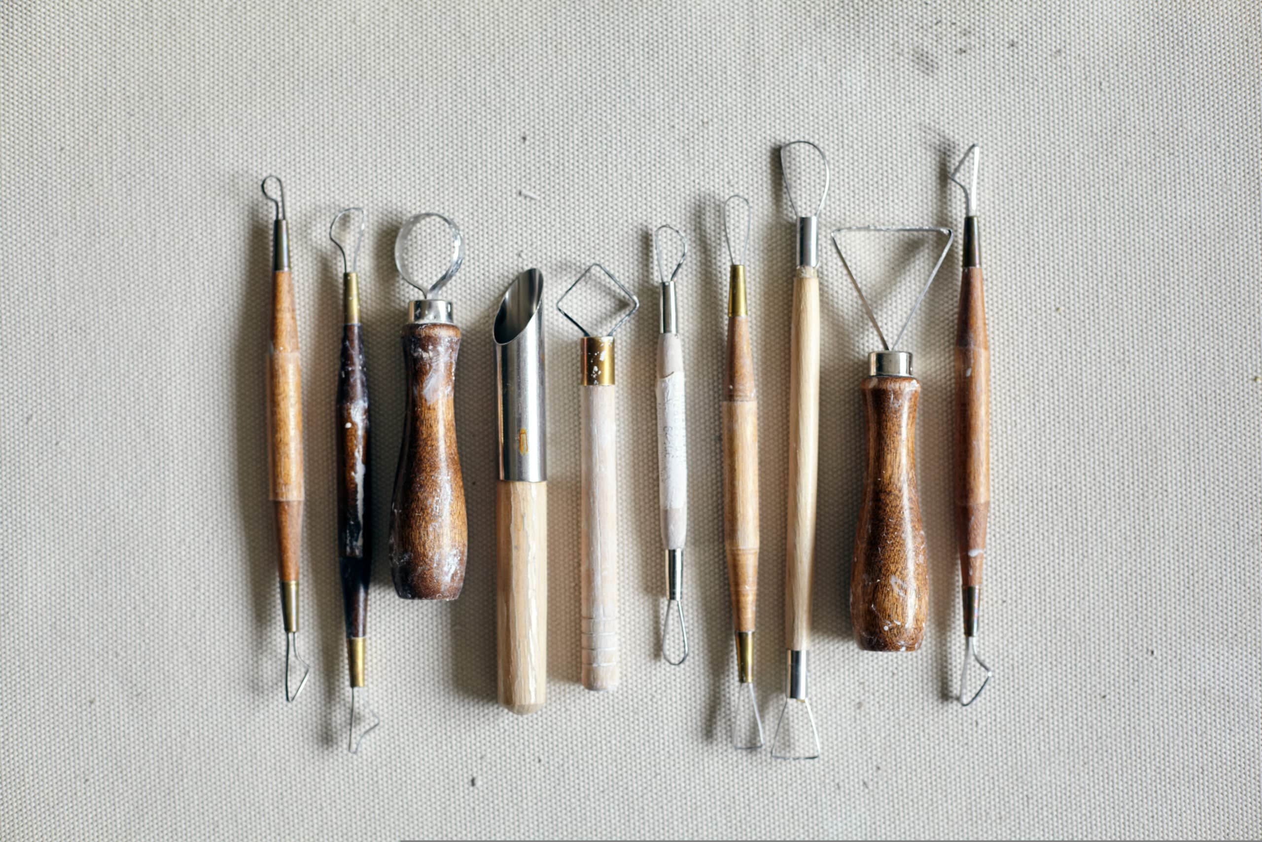 row of ceramic sculpting and carving tools for trimming and decoration on canvas surface