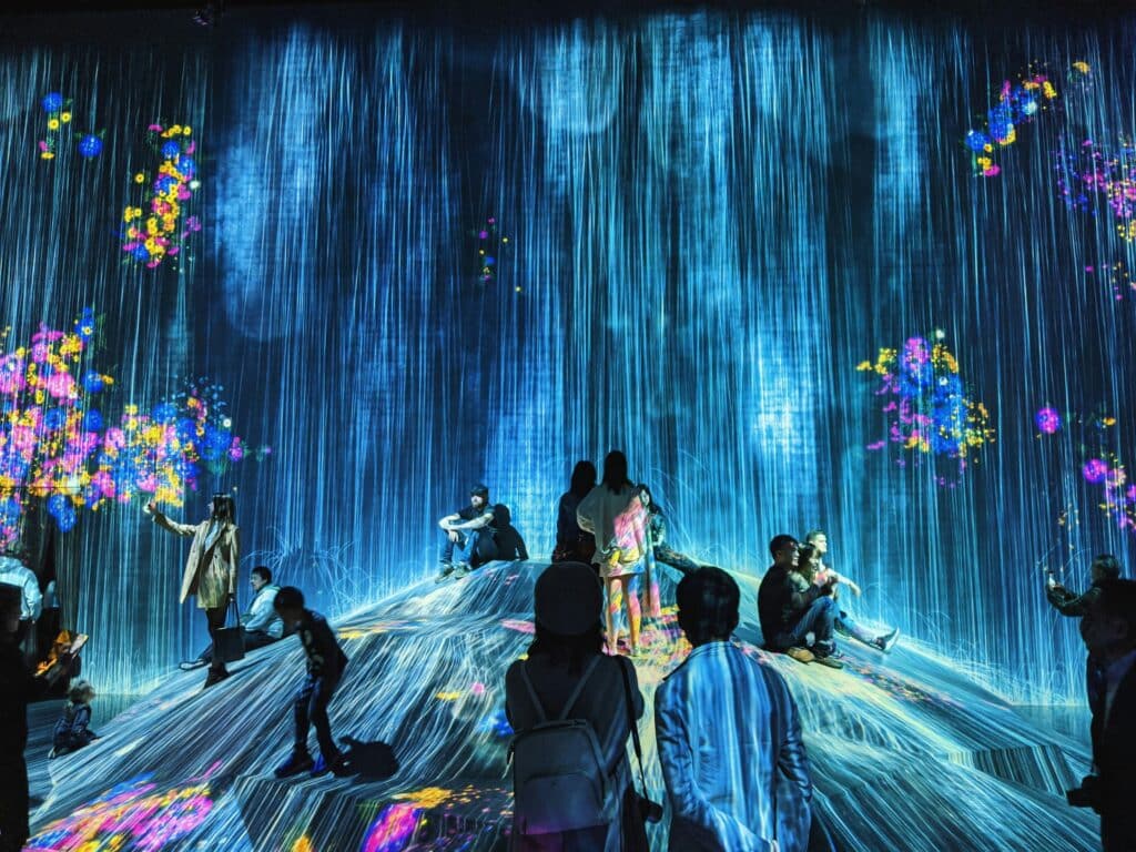 pessoas em pé em uma colina arredondada no palco com luzes azuis e multicoloridas