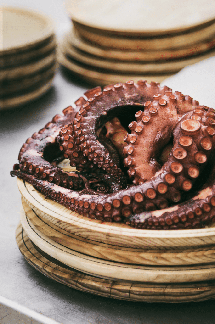 photo of mauve squid tentacles on a wooden plate by Sarah Pflug