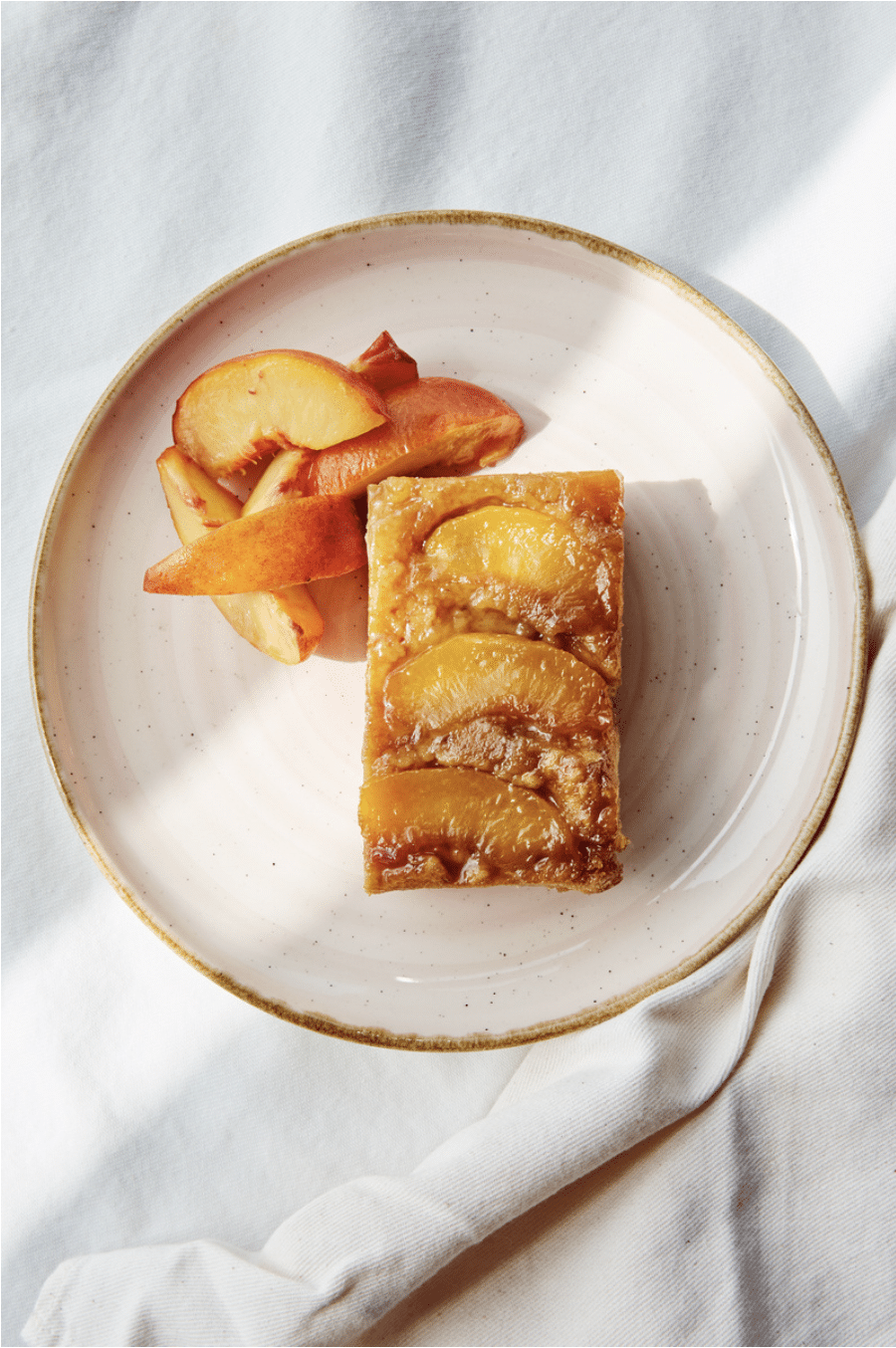 photo of upside down peach cake on a white speckled plate by Sarah Pflug