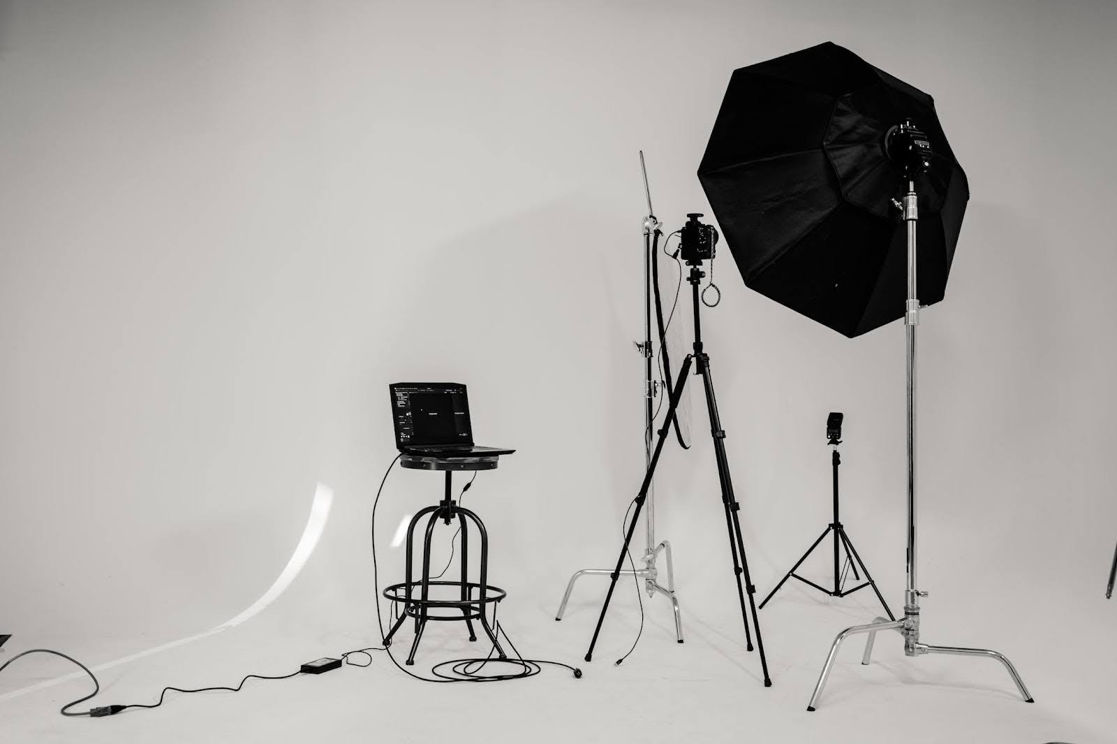 Strobe lighting setup with white backdrop, laptop, and umbrella reflector