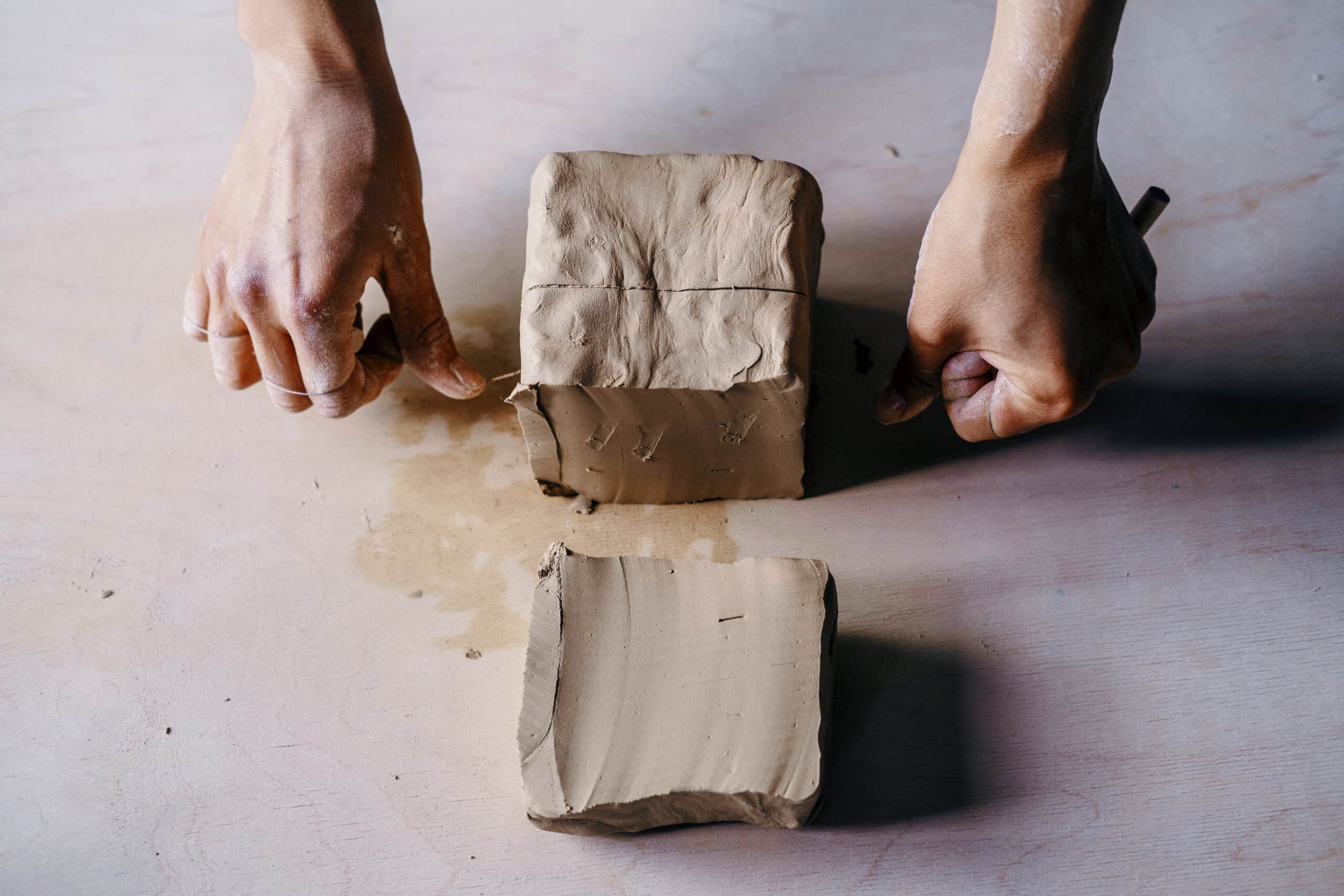 Female potter hands dividing clay in workshop