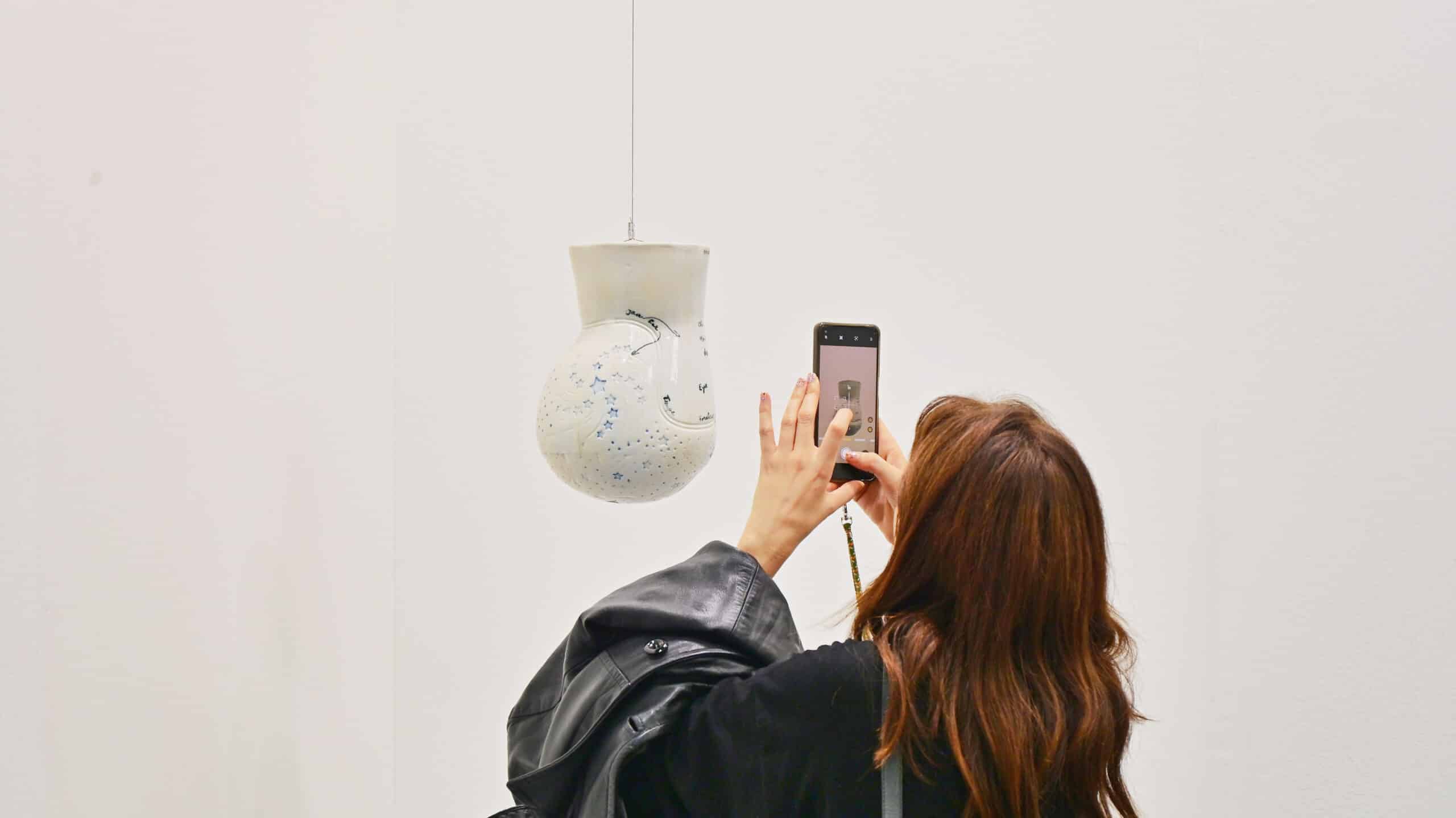 Woman taking photo of ceramic art installation at Artissima contemporary art fair for collectors and enthusiasts at Oval Lingotto pavillion Turin Italy November 2 2024